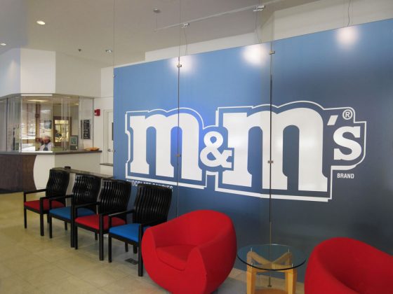 Blue panels with an M&M logo create a wall behind a row of chairs in the new waiting area inside the lobby.