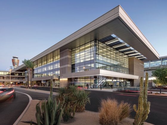 Evening view of modern, multistory airport terminal with large glass walls.