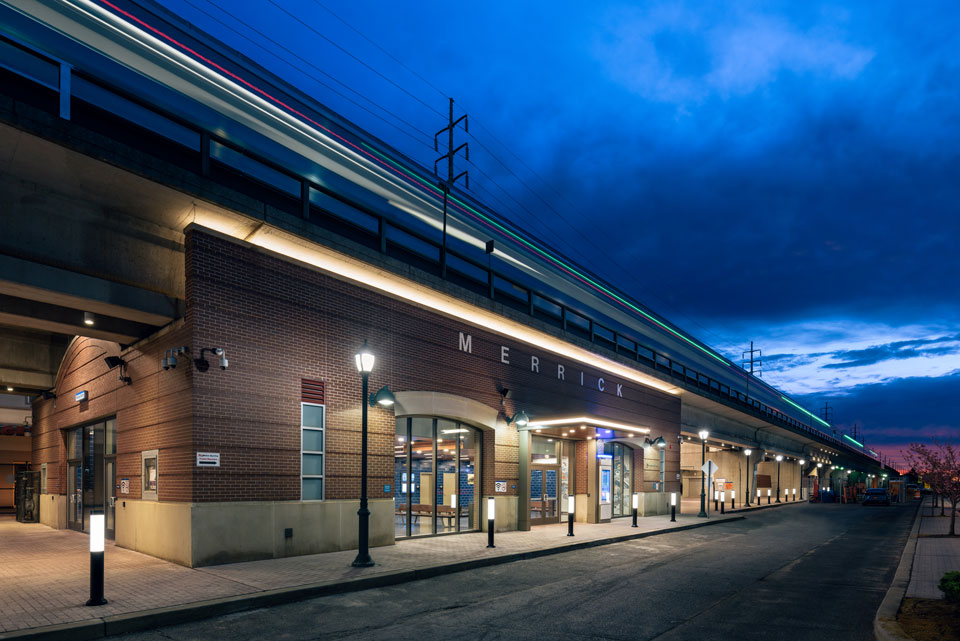 Exterior of Merrick Station at night shows new lighting and training passing through rooftop platform.