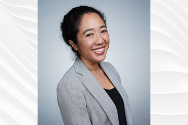 A female professional in a gray suit has dark hair pulled into a bun.