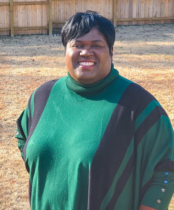 A portrait of a woman wearing a black and green sweater posing and smiling.