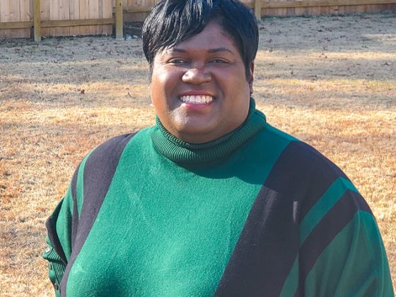 A portrait of a woman wearing a black and green sweater posing and smiling.