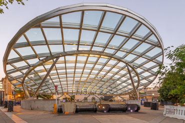 Steel and glass canopy structure covering the entrance to a subway station.