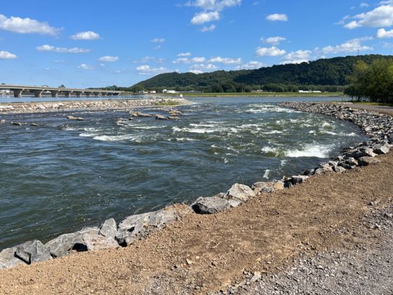 Water briskly moves through a channel lined with large rocks.