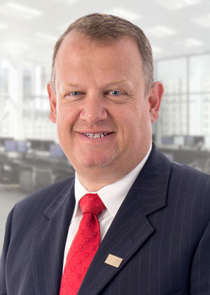 Smiling man wearing a white shirt, red tie, and blue pinstripe suit.