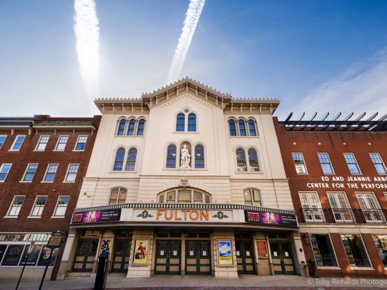 Historic theatre building with marquee sign that says Fulton. There are brick buildings on either side of the theater.