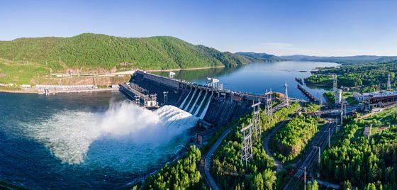 Ariel view of water flowing from a hydropower dam along a river.