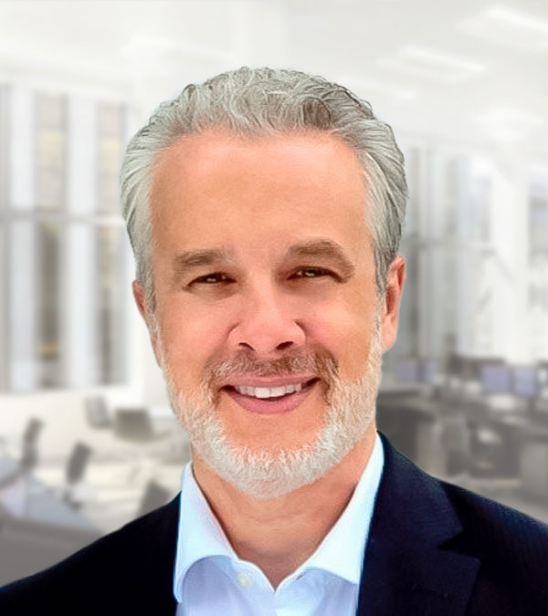 A professional headshot of a man with gray hair in a dark business suit.