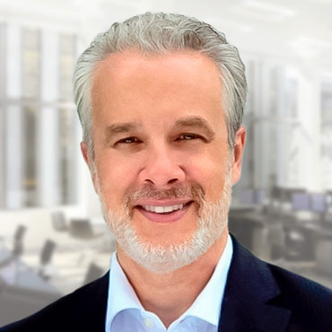 A professional headshot of a man with gray hair in a dark business suit.