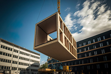 Crane lifting a wooden module to its position in a modular construction building.