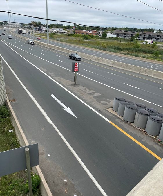 Looking down at the exit from an eight-lane highway with impact attenuators between the road and the exit lane.