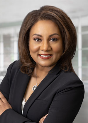 A woman with brown hair wearing a black outfit smiling for the camera.