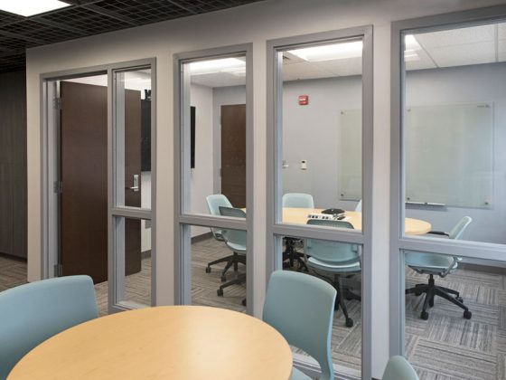 Conference room with table separated from the room in the foreground by a glass wall.