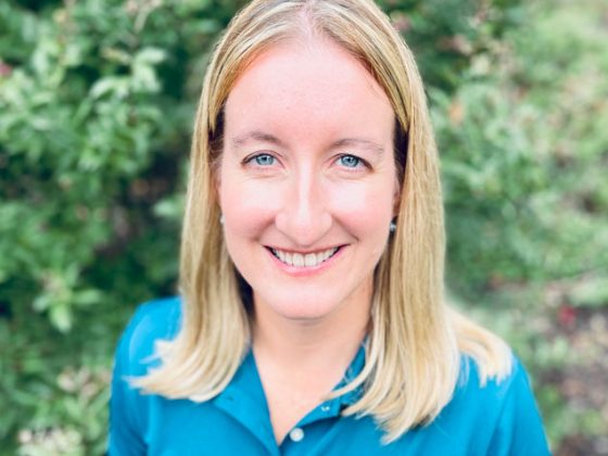 Wearing a blue shirt and standing outside, Watershed planning expert Kate Sharpe stands smiling.