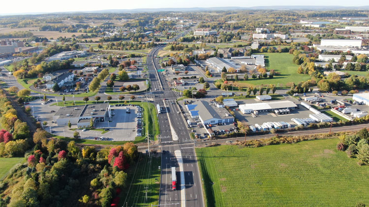 Arial view of a vertical six-lane roadway with commercial buildings along both sides.