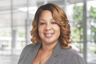 Portrait of Tamika Bass in a gray outfit smiling.