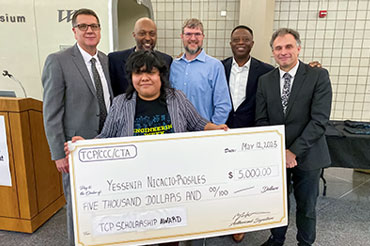 Undergraduate college student Yessenia Nicacio-Rosales holds a large cardboard check for the $5,000 TCP-CTA Transfer Scholarship at the City Colleges of Chicago-Wilbur Wright College with Bob Wittman (TCP Program Manager, Patrick Engineering), Robert Mitchell (TCP Workforce Development, ERS), William (Bill) R. Mooney (Chief Infrastructure Officer, CTA), Dennis Anosike (TCP JV Board Member, Gannett Fleming), and Dr. David Potash (President, Wilbur Wright College).