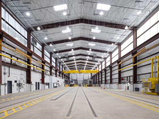 The interior of a large building with a locomotive and passenger rail car at the far end.