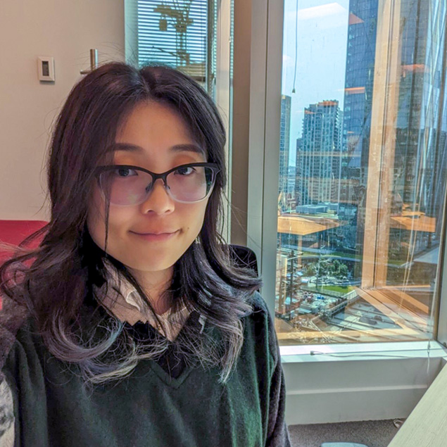 A woman posed in front of an open window, showing a cityscape.